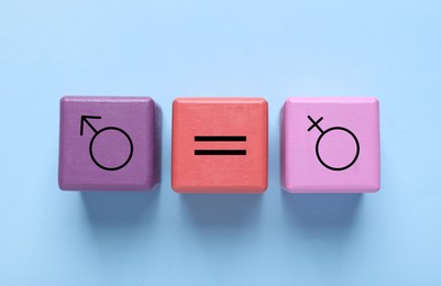 Image of Cube with equals sign between female and male gender symbols on light blue background, top view