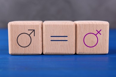 Cube with equals sign between female and male gender symbols on blue wooden table