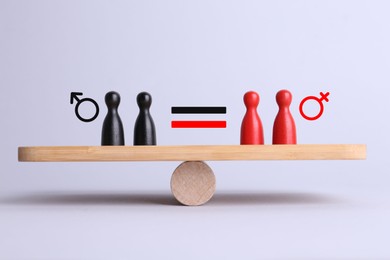 Wooden balance scales with pawns showing concept of equality between men and women