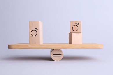 Wooden balance scales with cubes showing concept of equality between men and women