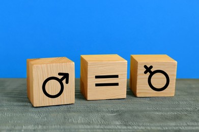 Cube with equals sign between female and male gender symbols on blue background