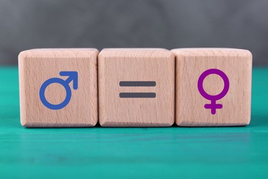 Image of Cube with equals sign between female and male gender symbols on turquoise wooden table