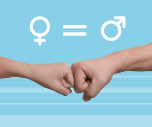 Gender equality concept. Man and woman making fist bump on light blue background, closeup