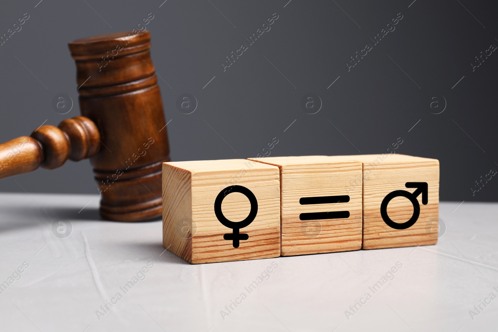 Image of Cube with equals sign between female and male gender symbols near wooden gavel on light table