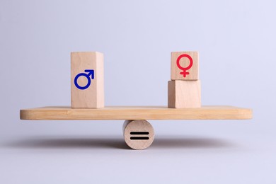 Wooden balance scales with cubes showing concept of equality between men and women