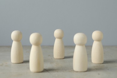 Photo of Many wooden human figures on grey table, closeup