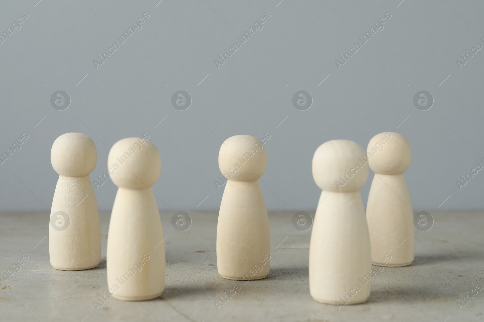 Photo of Many wooden human figures on grey table, closeup