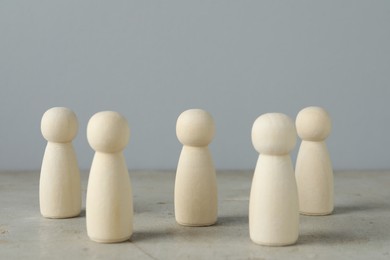 Photo of Many wooden human figures on grey table, closeup