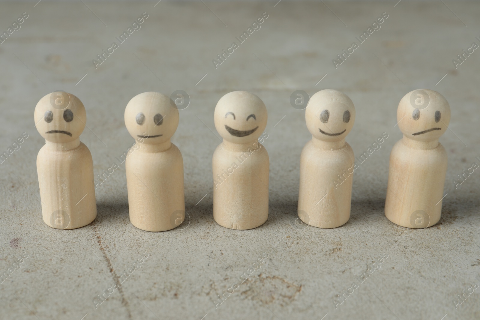 Photo of Wooden figures showing different emotions on grey table