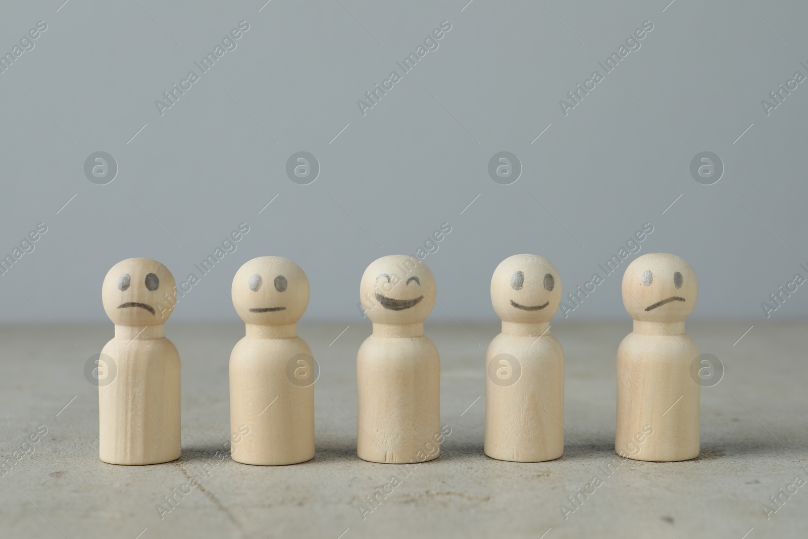 Photo of Wooden figures showing different emotions on grey table