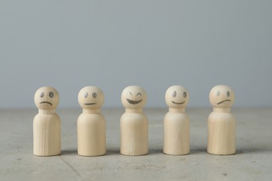 Photo of Wooden figures showing different emotions on grey table