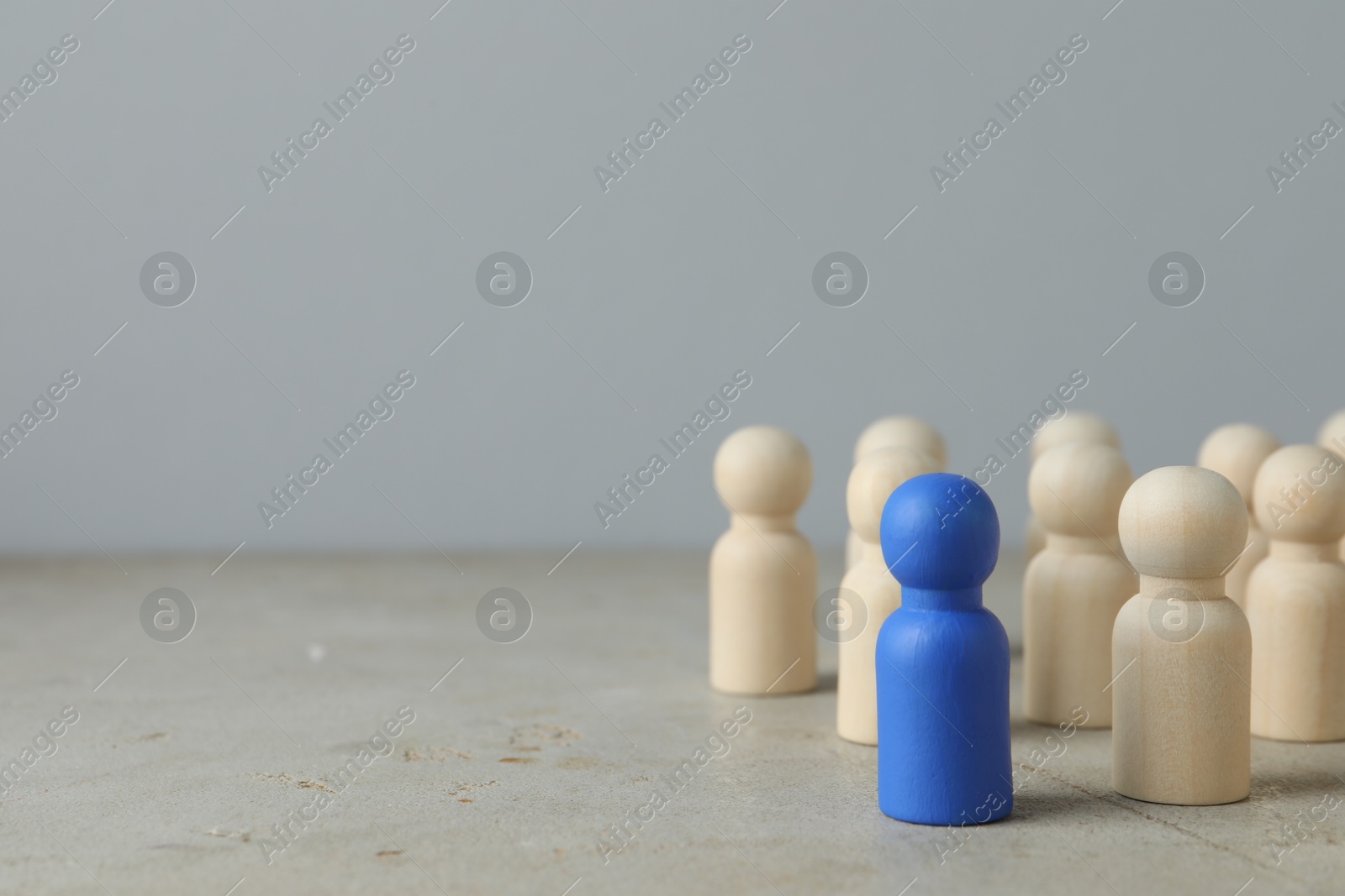 Photo of Blue piece among wooden ones on grey table. Space for text