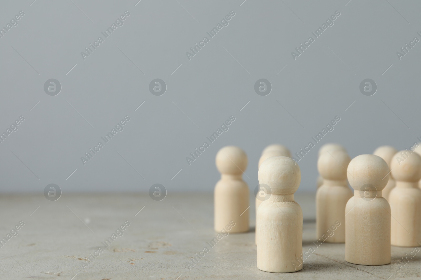 Photo of Many wooden human figures on grey table. Space for text