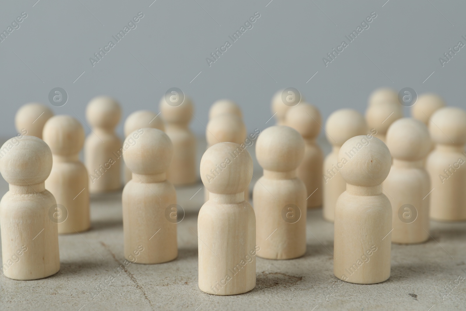 Photo of Many wooden human figures on grey table, closeup