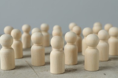 Many wooden human figures on grey table, closeup