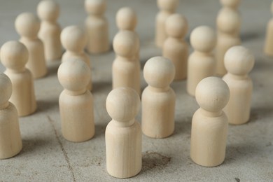 Photo of Many wooden human figures on grey table, closeup