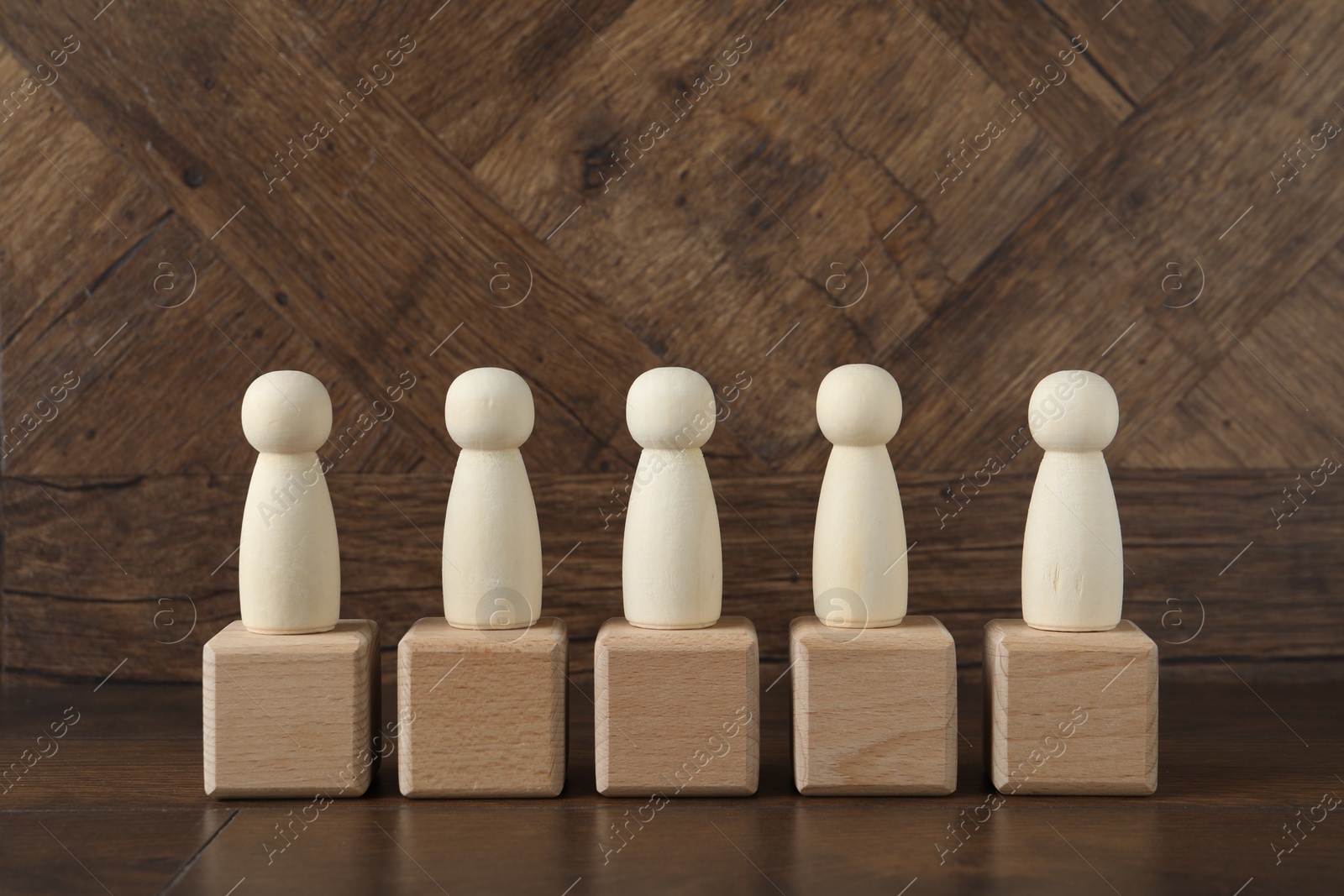 Photo of Many human figures on cubes against wooden background