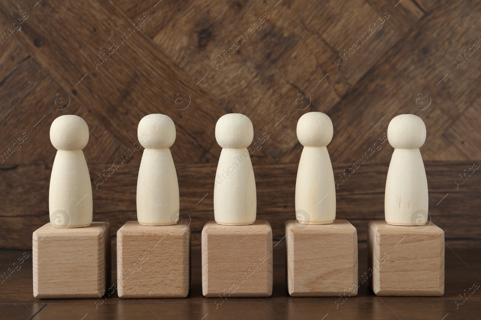 Photo of Many human figures on cubes against wooden background