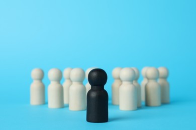 Photo of Black piece among wooden ones on light blue background