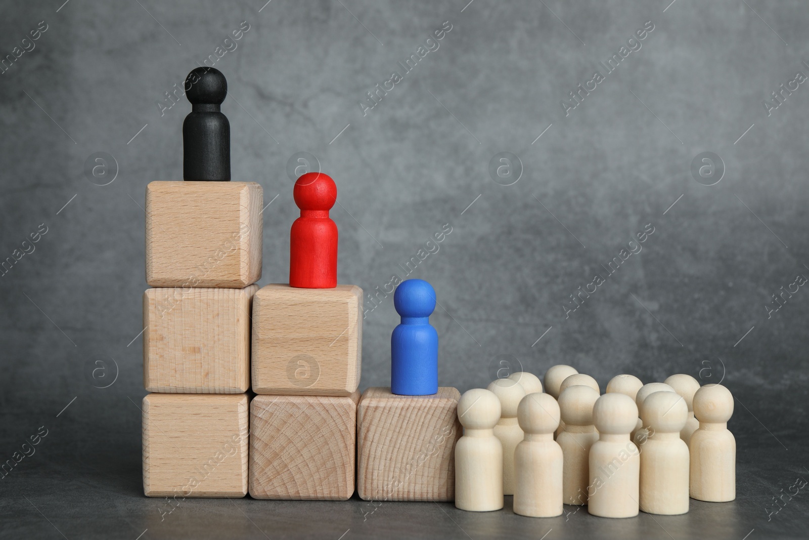 Photo of Different figures on wooden ladder against grey background