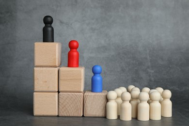 Different figures on wooden ladder against grey background