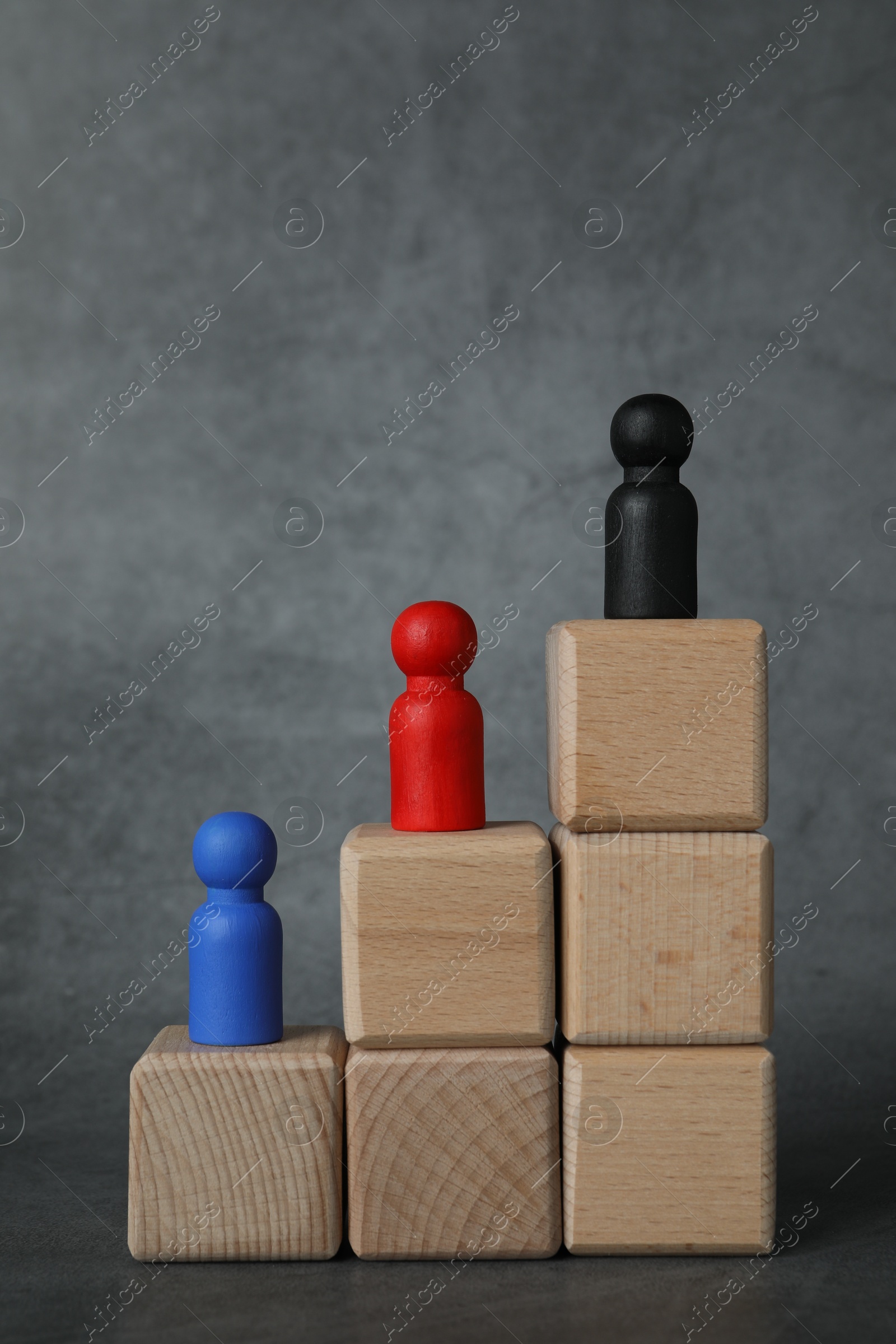 Photo of Different figures on wooden ladder against grey background