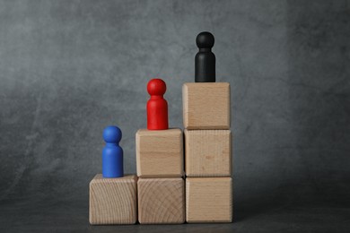 Photo of Different figures on wooden ladder against grey background