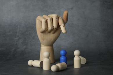 Blue piece among wooden ones and hand figure on grey table