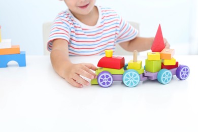 Photo of Little boy playing with toy at white table, closeup