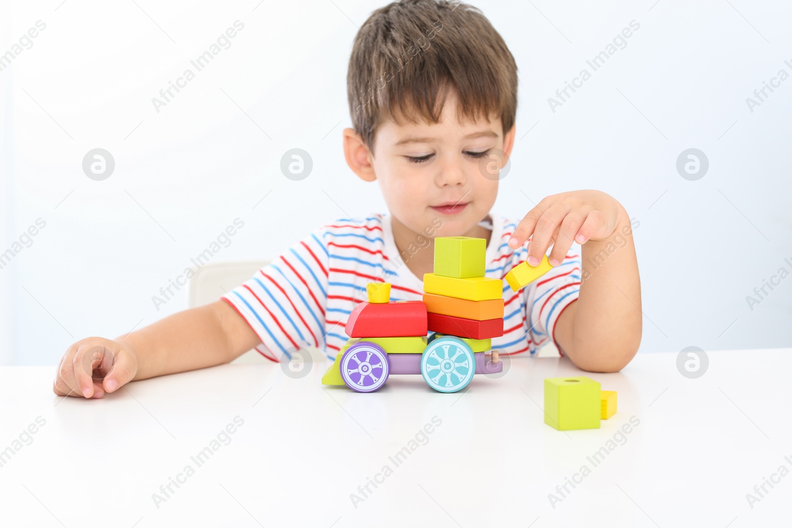 Photo of Little boy playing with toy at white table