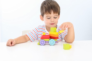 Little boy playing with toy at white table