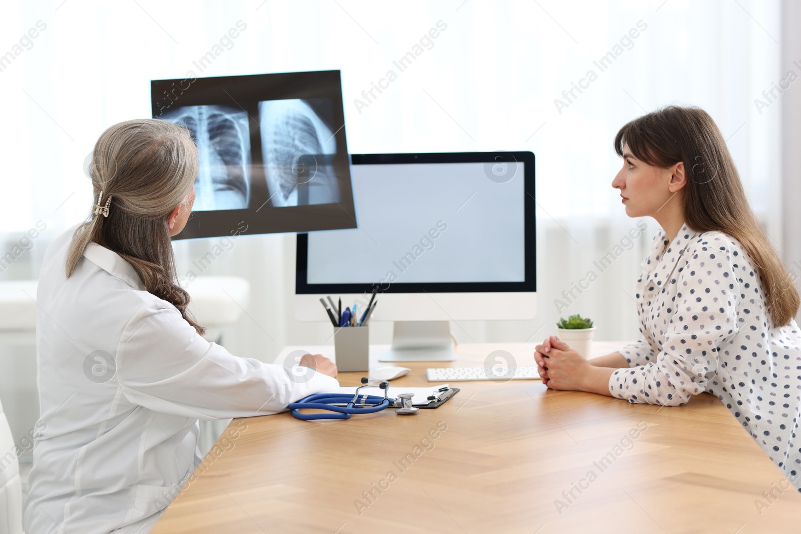 Photo of Lung disease. Doctor showing chest x-ray to her patient in clinic