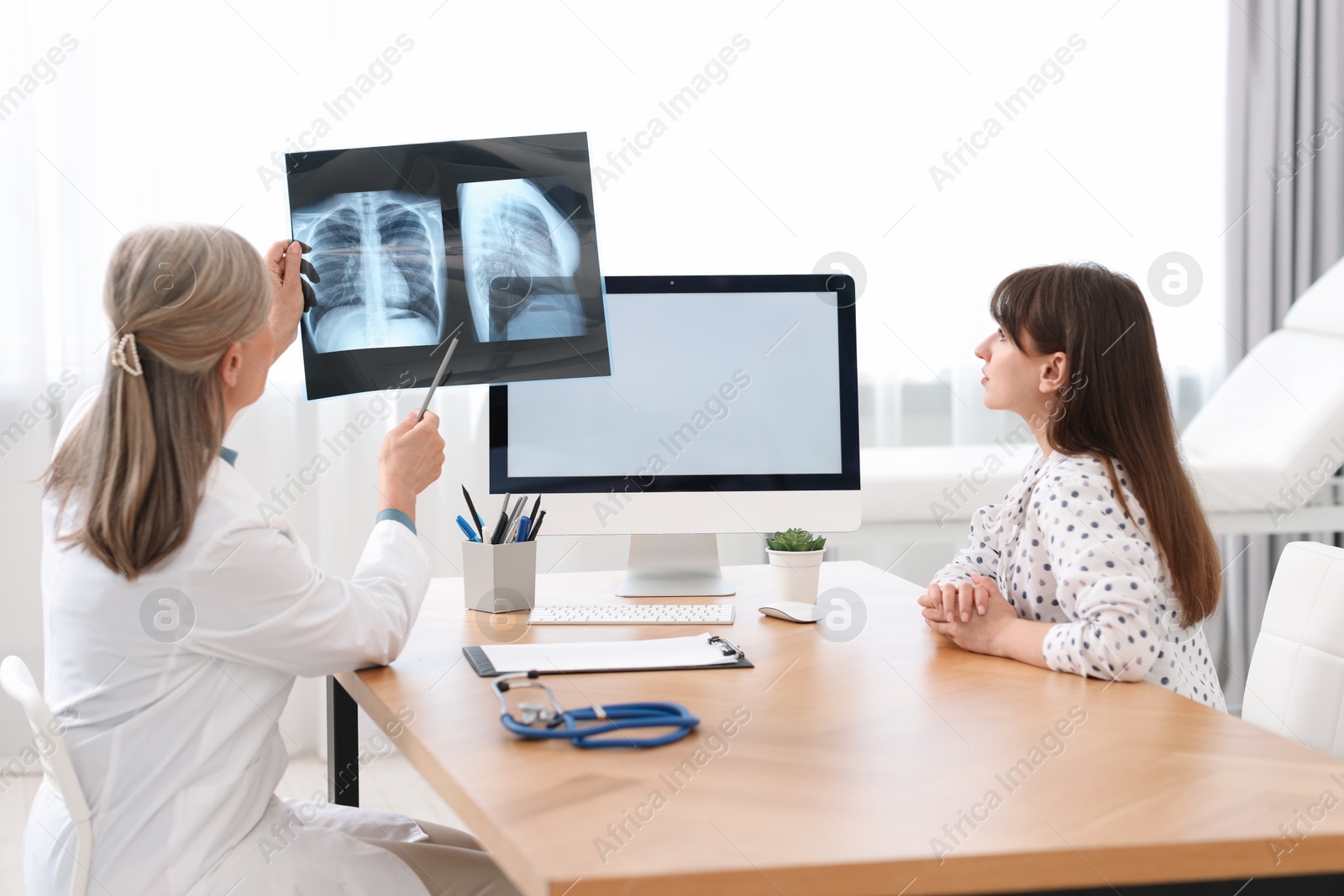 Photo of Lung disease. Doctor showing chest x-ray to her patient in clinic