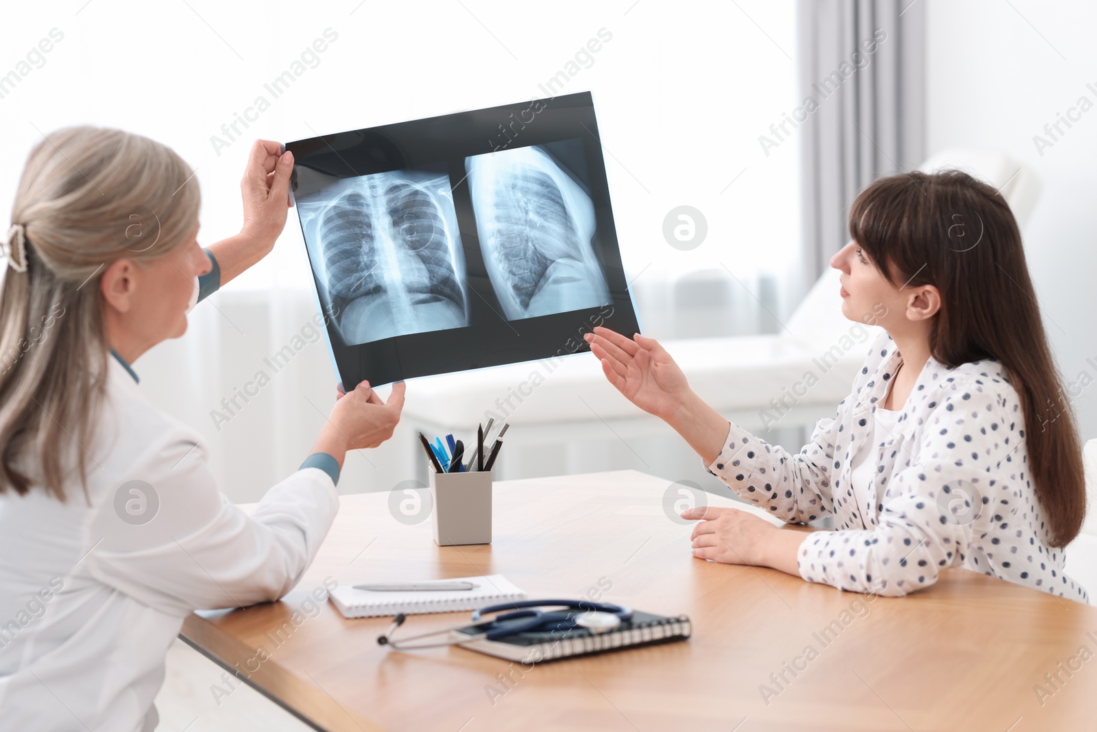 Photo of Lung disease. Doctor showing chest x-ray to her patient in clinic