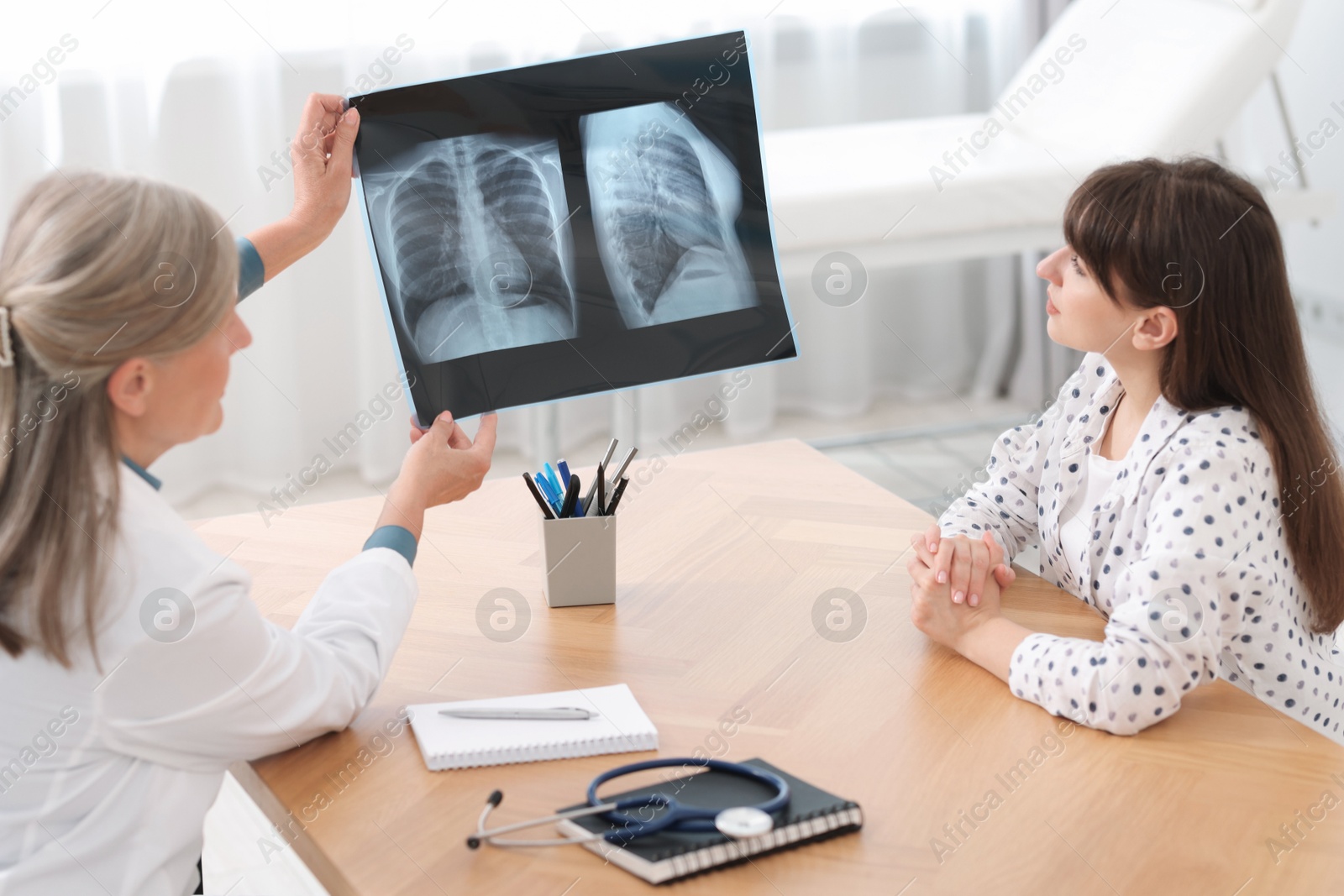 Photo of Lung disease. Doctor showing chest x-ray to her patient in clinic