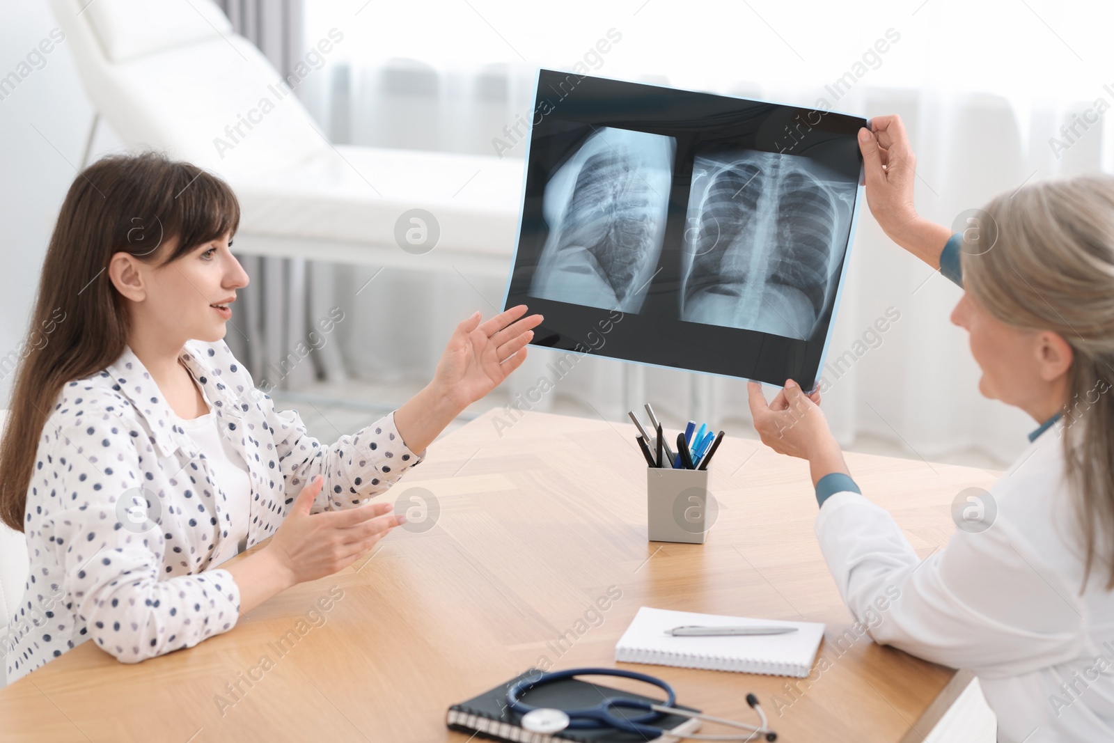 Photo of Lung disease. Doctor showing chest x-ray to her patient in clinic