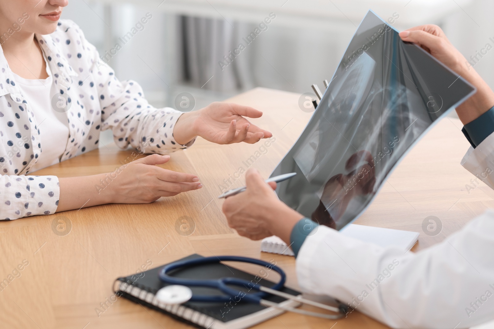 Photo of Lung disease. Doctor showing chest x-ray to her patient in clinic, closeup