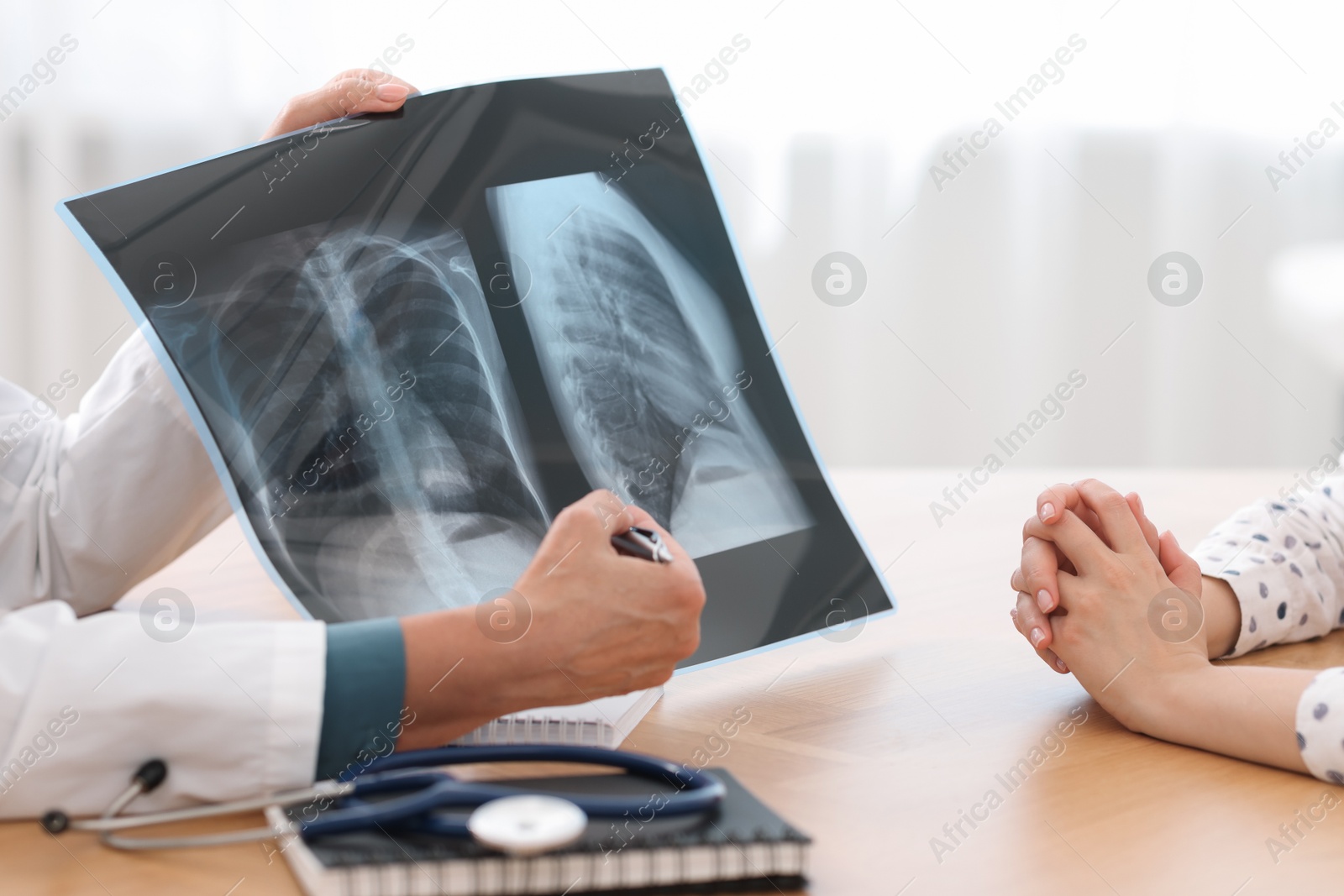 Photo of Lung disease. Doctor showing chest x-ray to her patient in clinic, closeup