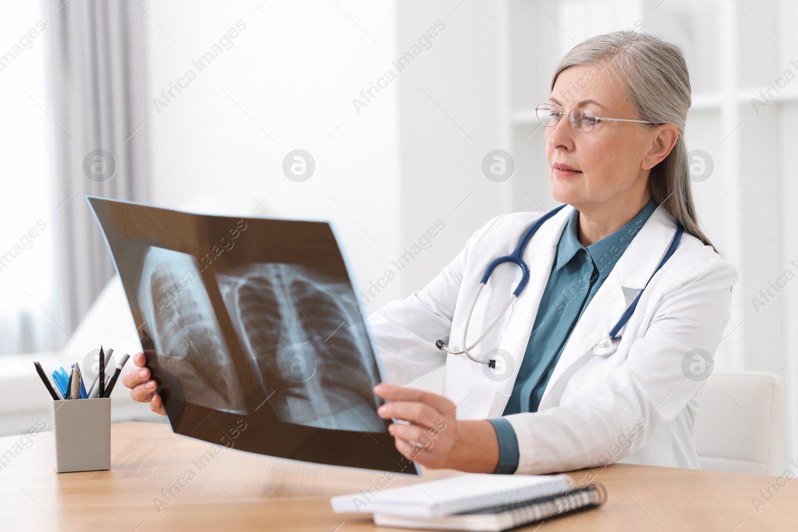 Photo of Lung disease. Doctor examining chest x-ray at table in clinic