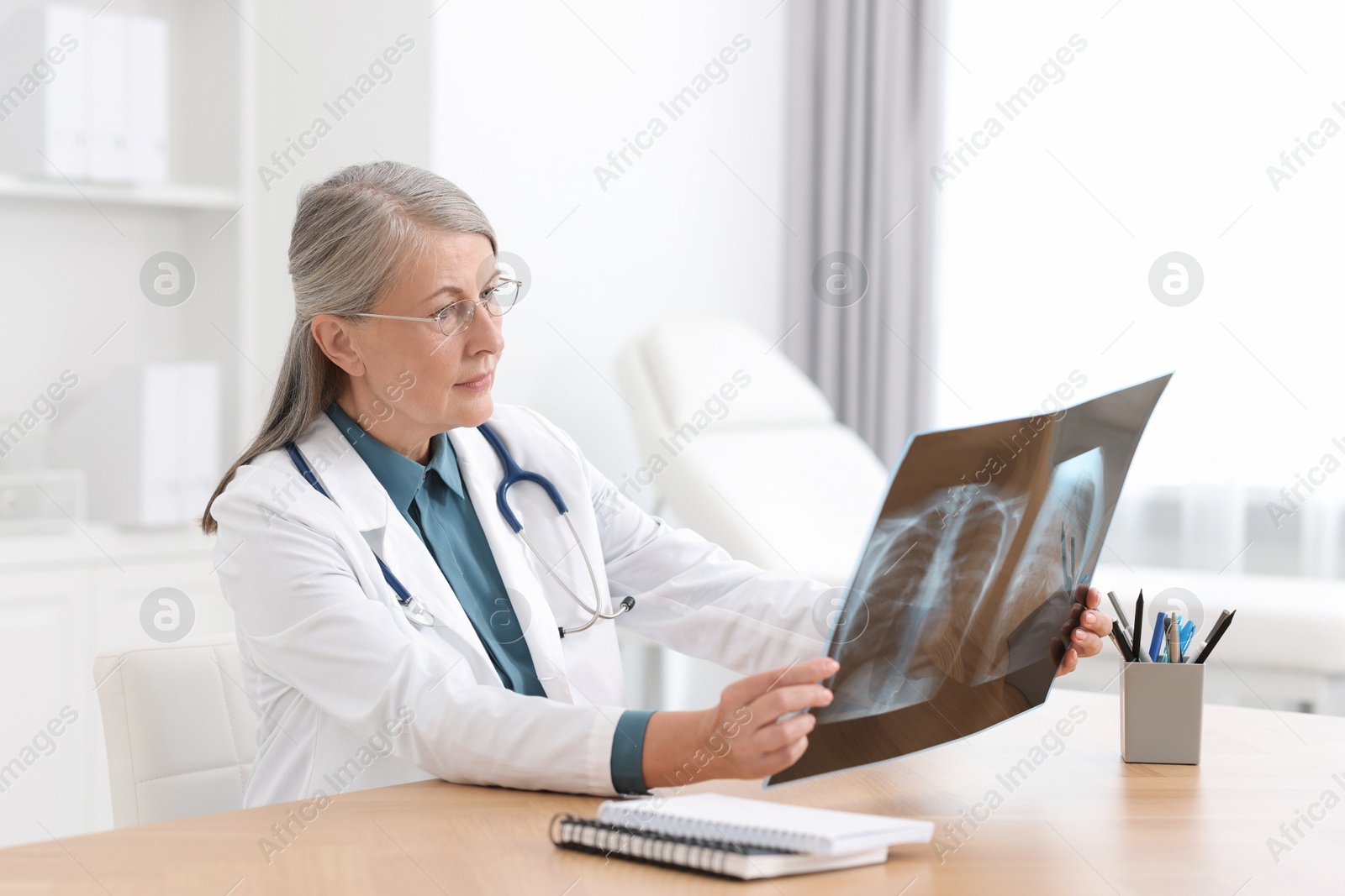 Photo of Lung disease. Doctor examining chest x-ray at table in clinic