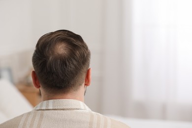 Photo of Baldness concept. Man with bald spot indoors, back view. Space for text