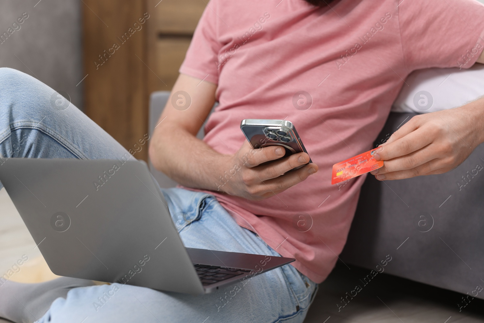 Photo of Online banking. Man with credit card, smartphone and laptop paying purchase at home, closeup