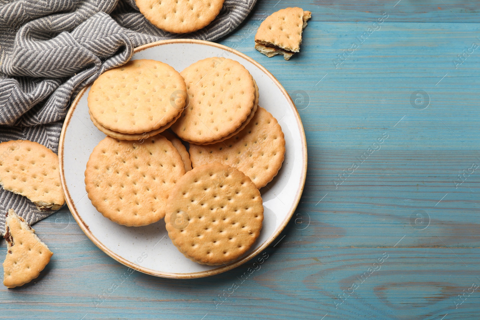 Photo of Tasty sandwich cookies on light blue wooden table, top view. Space for text