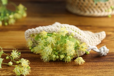 Fresh linden leaves and flowers on wooden table, closeup