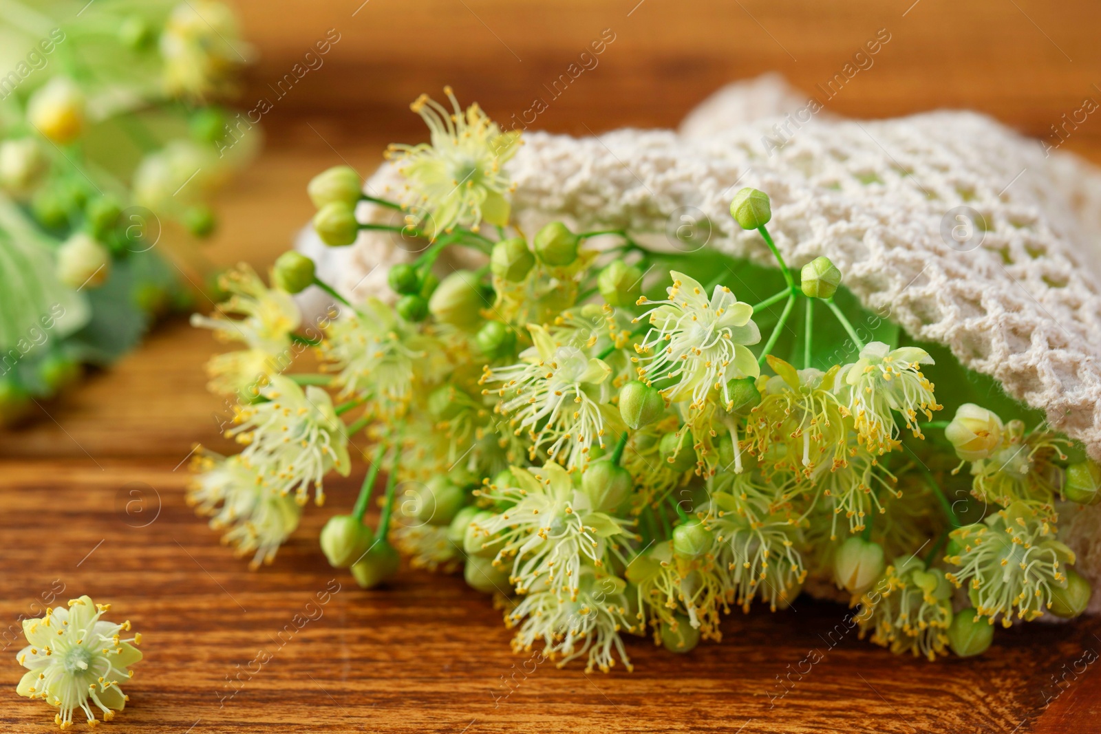 Photo of Fresh linden leaves and flowers on wooden table, closeup