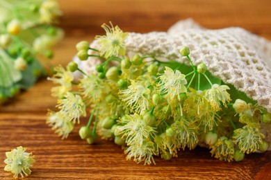 Fresh linden leaves and flowers on wooden table, closeup