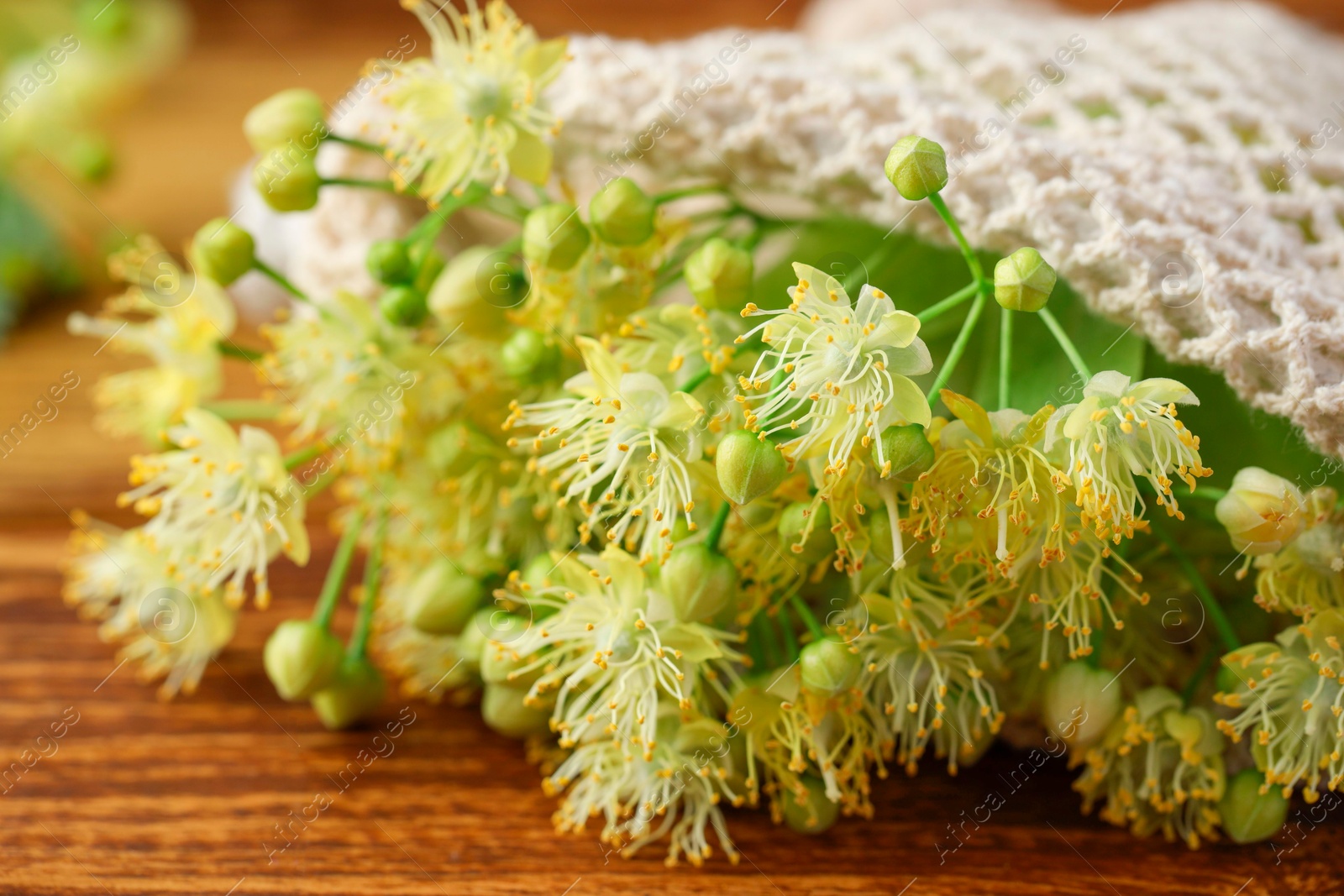 Photo of Fresh linden leaves and flowers on wooden table, closeup