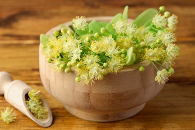 Photo of Fresh linden leaves and flowers on wooden table