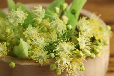 Fresh linden leaves and flowers on wooden table, closeup