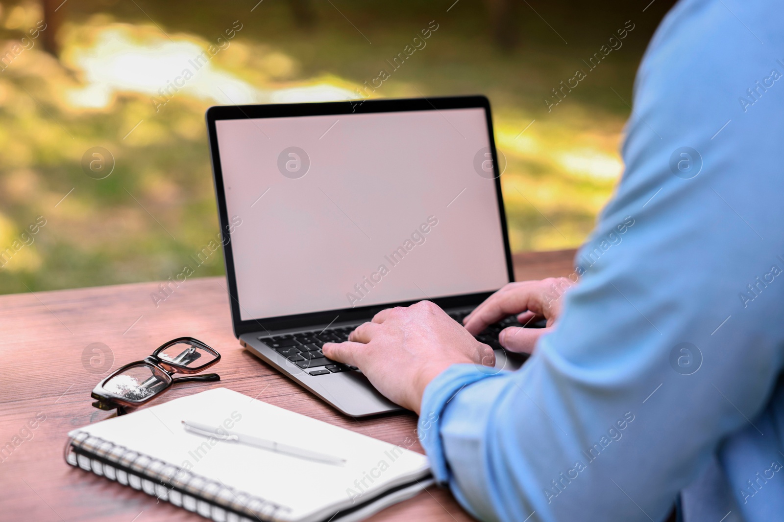 Photo of Freelancer working with laptop at table outdoors, closeup. Remote job